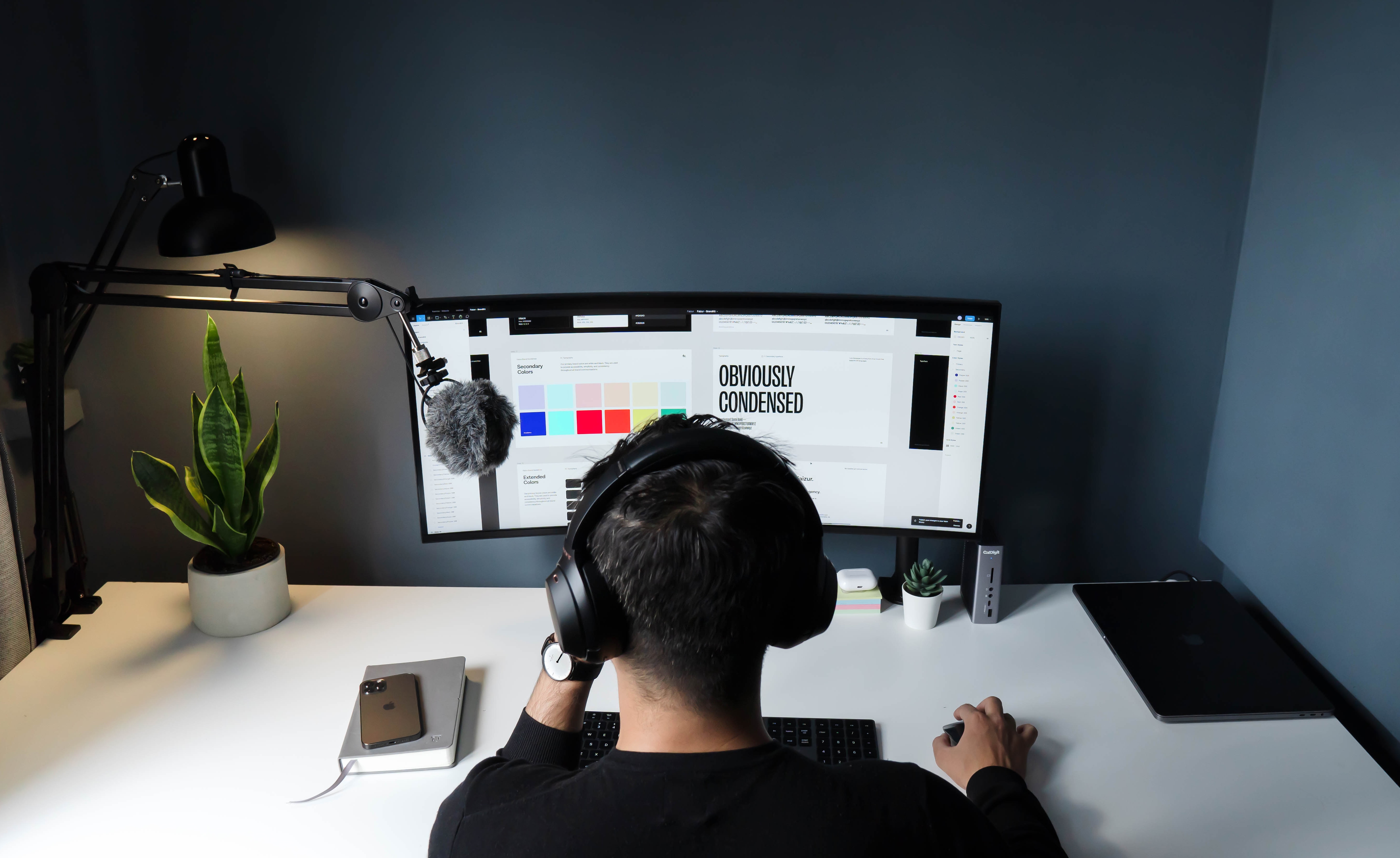 Designer working at a large monitor with a brand layout and color palette on screen.